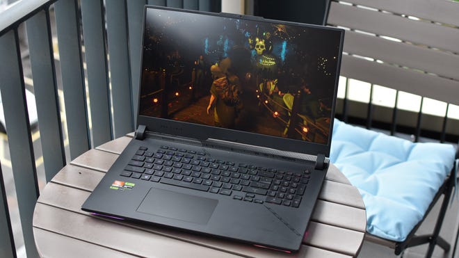 The Asus ROG Strix Scar 17 gaming laptop on a small outdoor table.